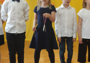 Dzieci śpiewają piosenkę. Dziewczynka gra na trójkącie.