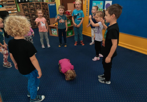 Zabawa ze śpiewem do muzyki. Dzieci w kole, a na środku leży skulone dziecko.