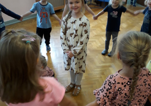 Dzieci w kole na sali gimnastycznej podczas zajęć rytmicznych śpiewają "100 lat".