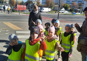 Dzieci machają do obiektywu po przejściu przez pasy.