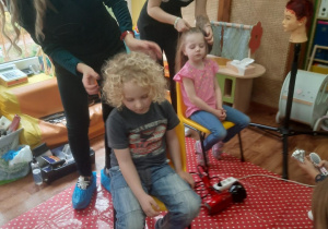 Pani Kasia i jej uczennica wykonują dzieciom fryzury.