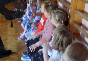 Dzieci siedzą na ławce i głaszczą puchacza.