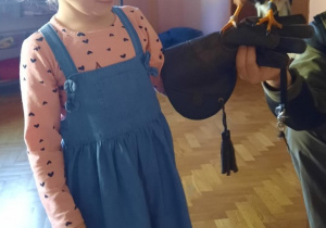 Dziewczynka trzyma na dłoni zabezpieczonej rękawicą myszołowa Azira.