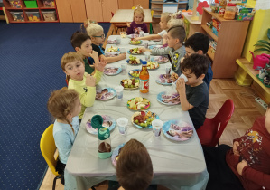 dzieci siedzą przy stole i świętują urodziny koleżanki