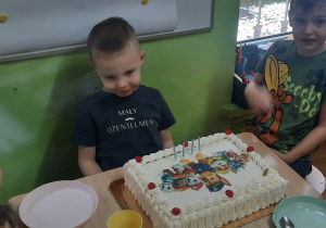 Chłopiec siedzi przed tortem.