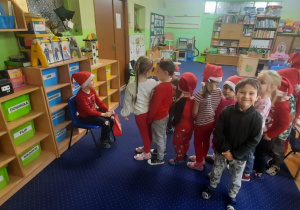 Dzieci ustawione w rządku składają życzenia Mikołajowi.
