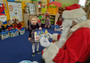 Mikołaj wręcza prezent dziecku.