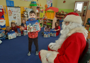 Mikołaj wręcza prezent dziecku.
