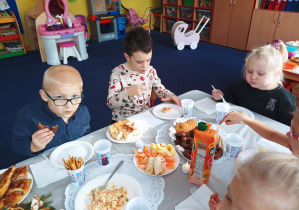 dzieci przy stoliku zjadają różne potrawy