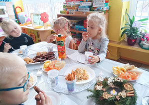 dzieci przy stoliku zjadają różne potrawy