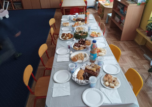 zdjęcie stołu, na którym widać talerze, słodycze, owoce, wigilijne potrawy, świąteczny stroik, świeczki