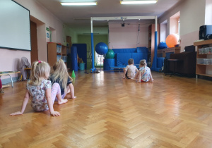 Dzieci przesuwają się na pupie po sali gimnastycznej