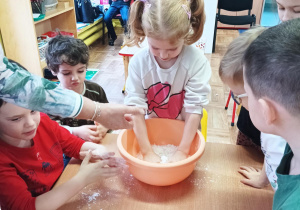 dzieci wykonują masy sensoryczne z mąki i oleju
