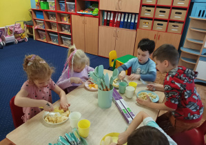 dzieci kroją owoce przy stolikach