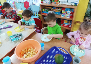 dzieci kroją owoce przy stolikach