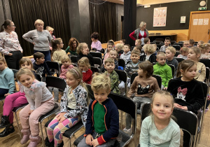 Dzieci siedzą na krzesełkach w oczekiwaniu na przedstawienie.