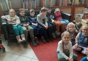 Dzieci siedzą w bibliotece.