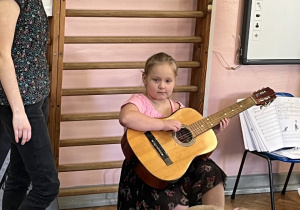 Dziewczynka próbuje grać na gitarze.