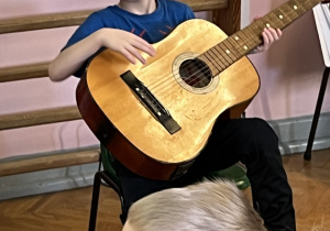 Chłopiec próbuje grać na gitarze.