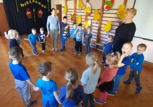 grupa dzieci ubrana na niebiesko tańczy w dużym kole na sali gimnastycznej