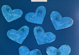 Prace plastyczne dzieci. Niebieskie serca z napisem autyzm i niebieskimi motylami.