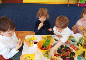 dzieci siedzą przy stolikach, na których widać świąteczne dekoracje, kolorowe serwetki, smakołyki na talerzach