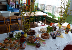 Wielkanocny stół na którym stoją smakołyki dla dzieci.