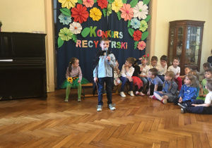 Chłopiec recytuje swój wiersz przed publicznością.