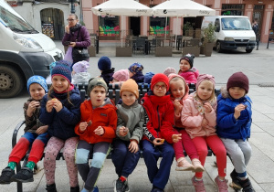 grupa dzieci siedzi na ławeczce na ulicy Piotrkowskiej