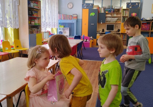dziewczynka częstuje dzieci cukierkami z kolorowej torebki