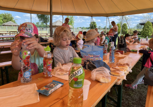 Dzieci siedzą przy stołach i zjadają posiłek.