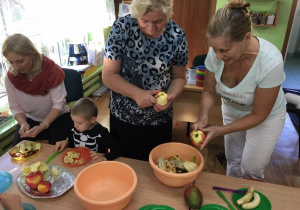 Dzieci wraz z babciami przygotowują sałatkę owocową,