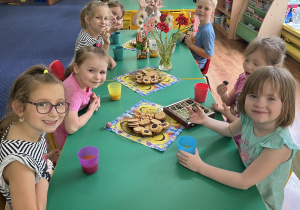 Dzieci siedzą przy stole na którym stoją słodkości. Nasze ostatnie przedwakacyjne takie drugie śniadanie.