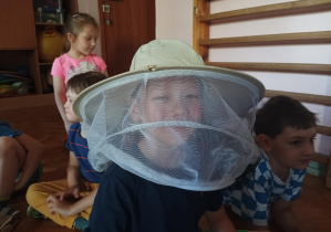 chłopiec pozuje do zdjęcia, na głowie ma kapelusz pszczelarza