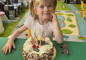Dziewczynka siedzi przed tortem.