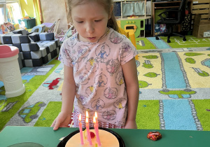 Dziewczynka zdmuchuje płonące świeczki.