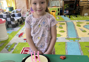 Dziewczynka stoi przed tortem.