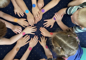 Dzieci wystawiają ręce na której naklejona jest kropka.