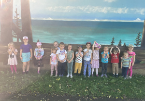 Dzieci pozują na tle narysowanego morza.