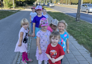 Dzieci pozują stojąc na chodniku.