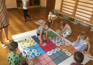Dzieci siedzą na podłodze i układają obrazki zgodnie z kodem.
