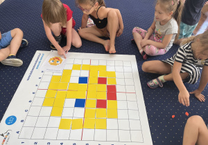 Dzieci układają kolorowe karteczki zgodnie z kodem.