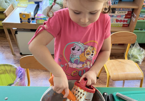 Dziewczynka ściera marchewkę.