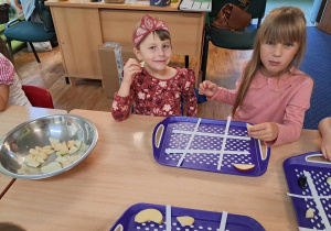 Dzieci siedzą przy stoliku i wykonują owocowe sudoku.