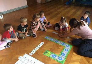 Dzieci siedzą na podłodze i układają drogę dla ozobota z puzzli.