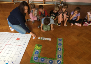 Dzieci siedzą na podłodze i układają drogę dla genibota.