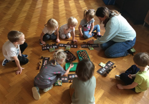 Dzieci siedzą na podłodze i układają rytmy.
