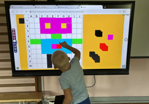 Dziecko wykonuje zadanie na tablicy multimedialnej.