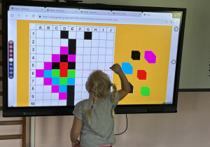Dziecko wykonuje zadanie na tablicy multimedialnej.