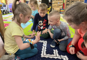 Dzieci siedzą na dywanie i układają drogę z puzzli dla ozobota.